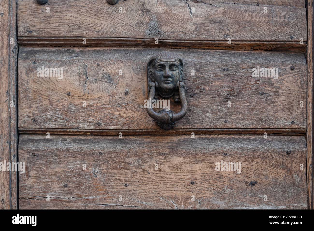 Primo piano di una vecchia porta di legno con un battente di ferro a forma di testa di un faraone egiziano, l'Italia Foto Stock