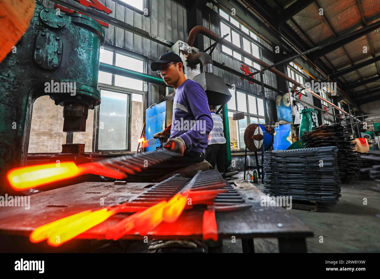 CONTEA DI LUANNAN, Cina - 24 settembre 2021: I lavoratori lavorano intensamente su una linea di produzione di forgiatura in uno stabilimento di produzione di utensili hardware nel nord della Cina Foto Stock