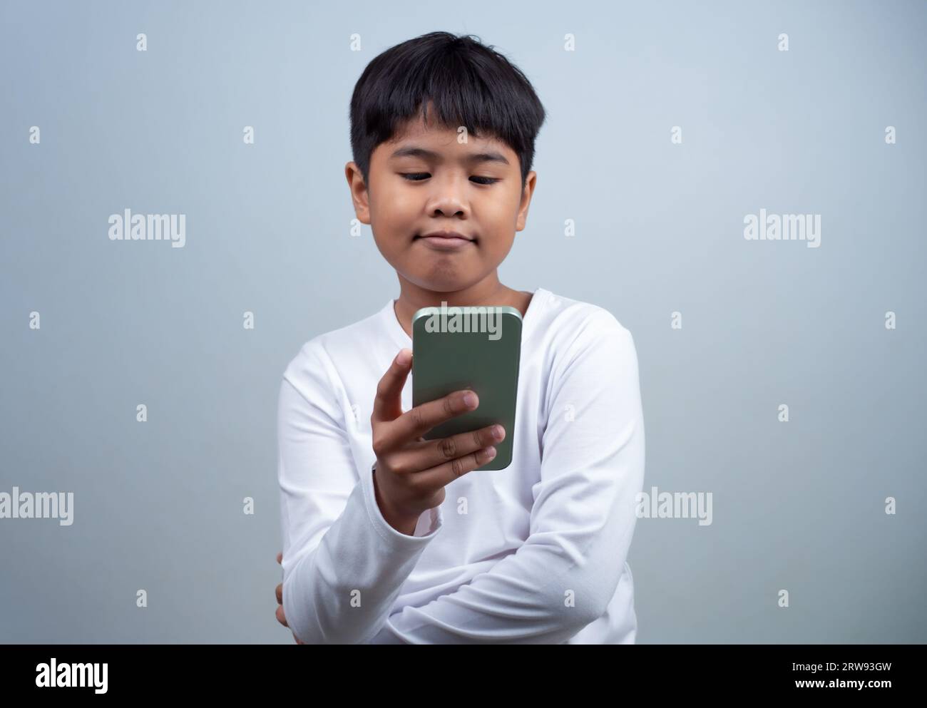 Concetti di social media e tecnologia. Le mani di un bambino che tiene uno smartphone e una matita stilo per utilizzare i contenuti multimediali e i social media per comunicare. Foto Stock
