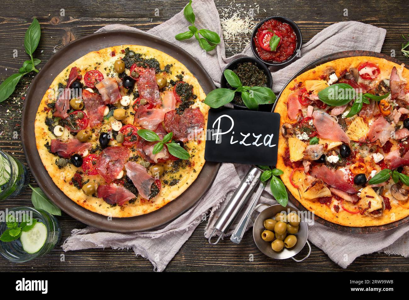 Pizze calde e gustose pronte da mangiare. Pizza fatta in casa per gli amanti della carne con peperoni e pancetta su uno sfondo di legno, vista dall'alto. Foto Stock