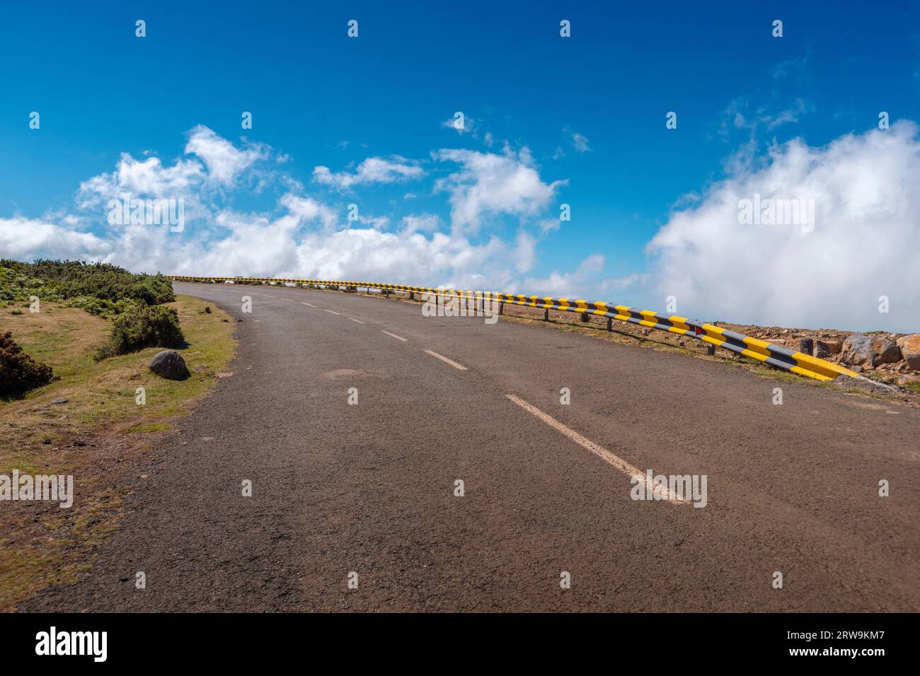 La strada di montagna di Madeira gira con un cielo blu brillante sullo sfondo Foto Stock