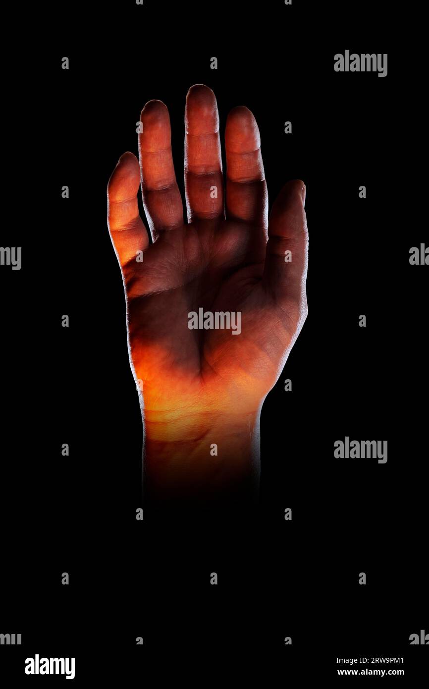 Bizzarra immagine di una mano, illuminata con luce arancione dal basso Foto Stock