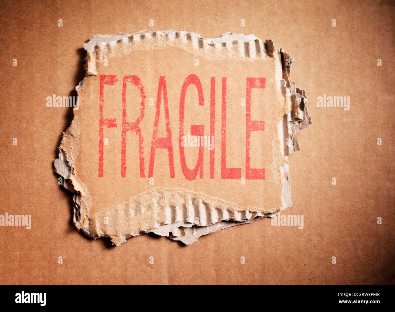 Parola fragile stampigliata su un pezzo di cartone ondulato marrone Foto Stock
