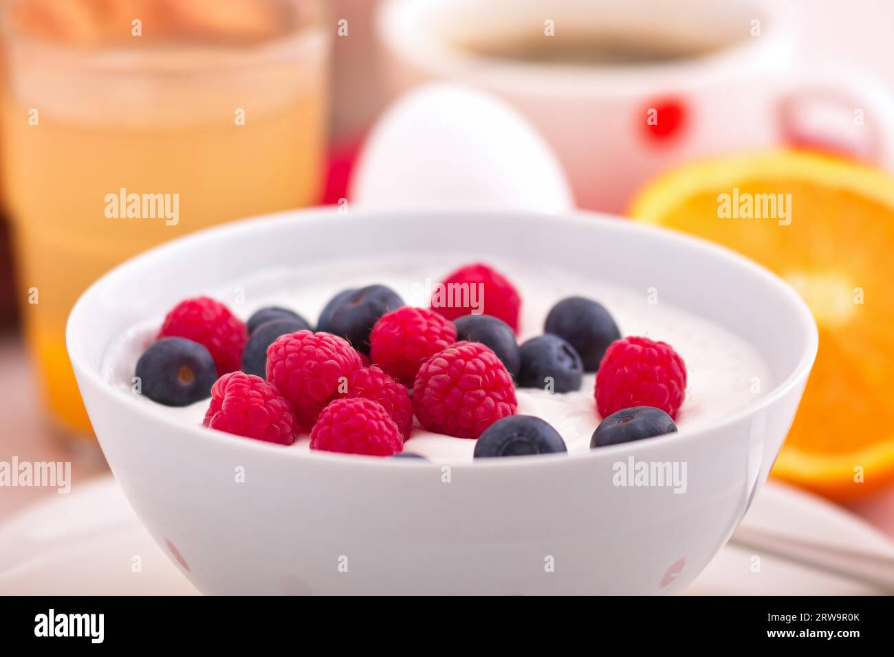 Un piatto di cagliata di frutta con lamponi freschi e mirtilli su un tavolo per la colazione Foto Stock