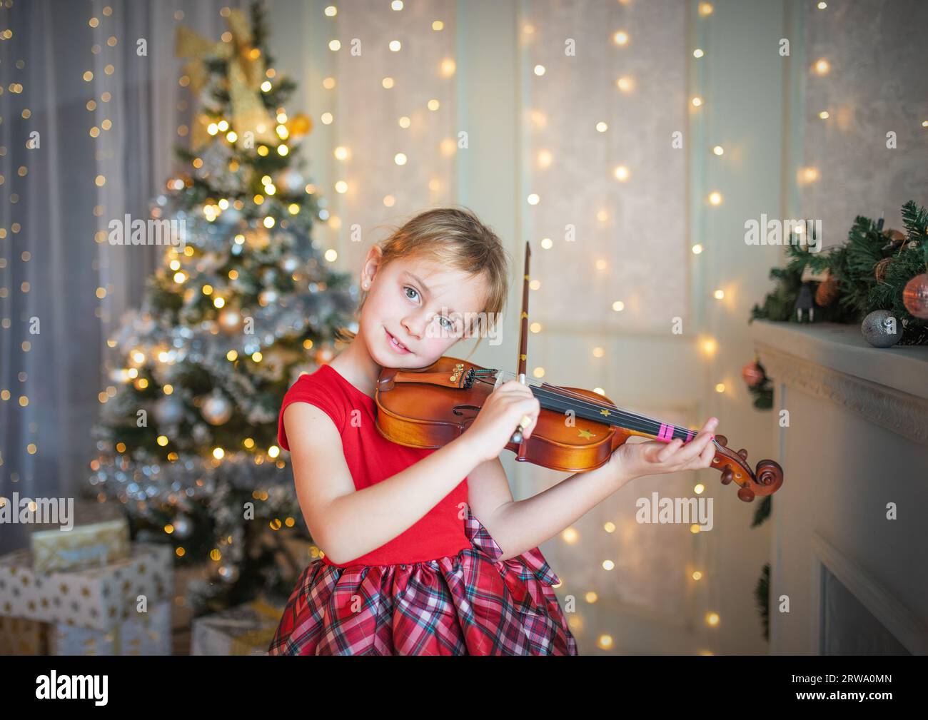 Giovane ragazza suona il violino nella parte anteriore dell albero di natale Foto Stock