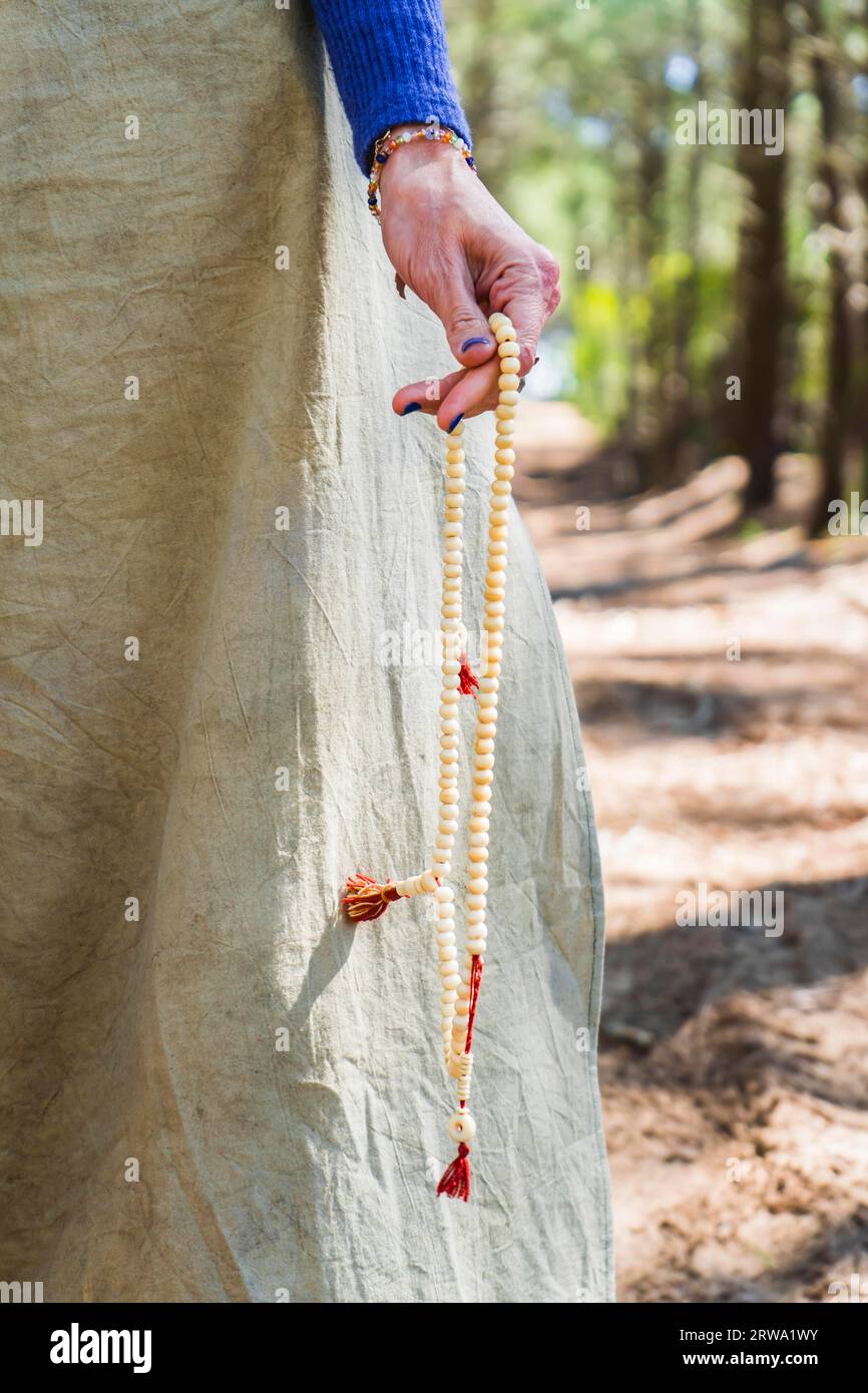 Primo piano di un japa mala saccheggiato da una mano di donna Foto Stock