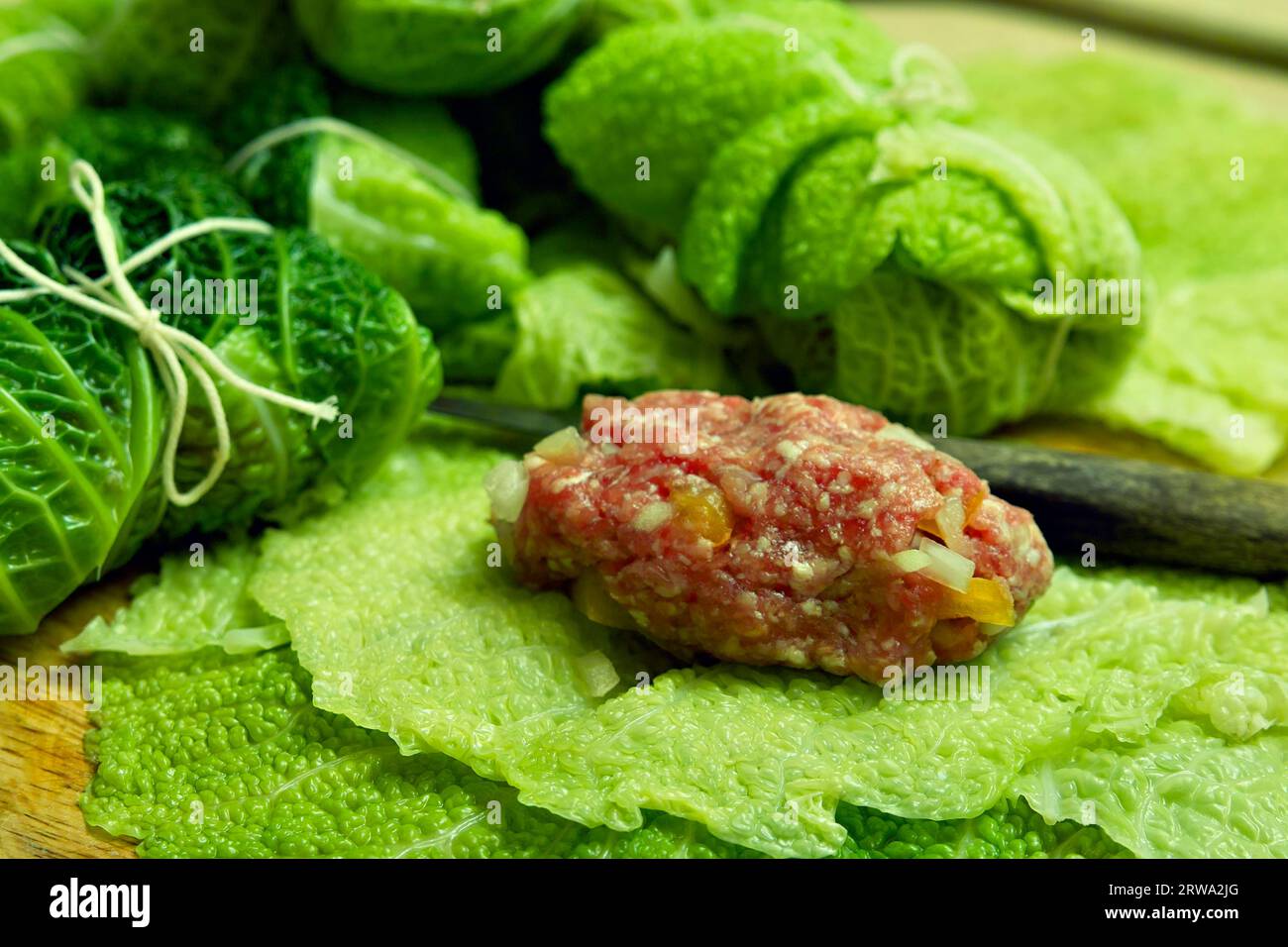 Una porzione di carne macinata si trova su foglie di cavolo savoy pronte per la preparazione dei rotoli di cavolo savoy Foto Stock