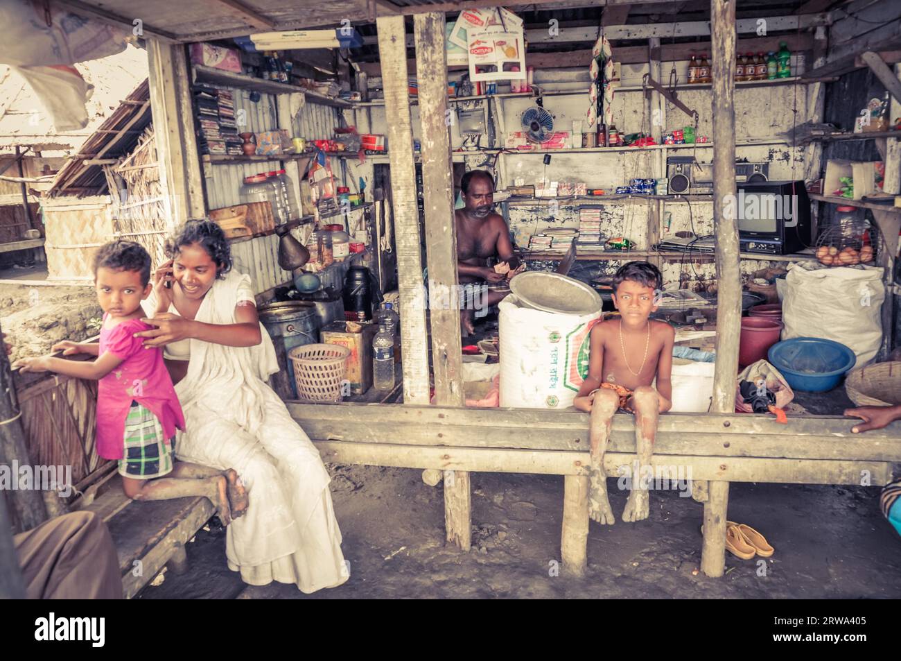 Sunderban, Bangladesh, circa luglio 2012: Famiglia nativa siede nella loro casa e i bambini scalzi guardano alla macchina fotografica a Sunderban, Bangladesh. Foto Stock