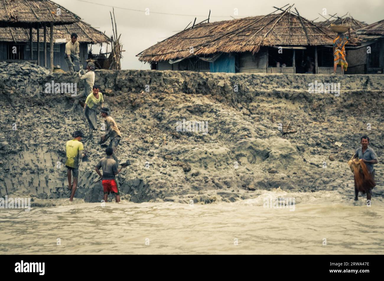 Sunderban, Bangladesh, circa luglio 2012: Uomini nativi lavorano nel fango vicino alle loro case e al fiume a Sunderban, Bangladesh. Documentario editoriale Foto Stock