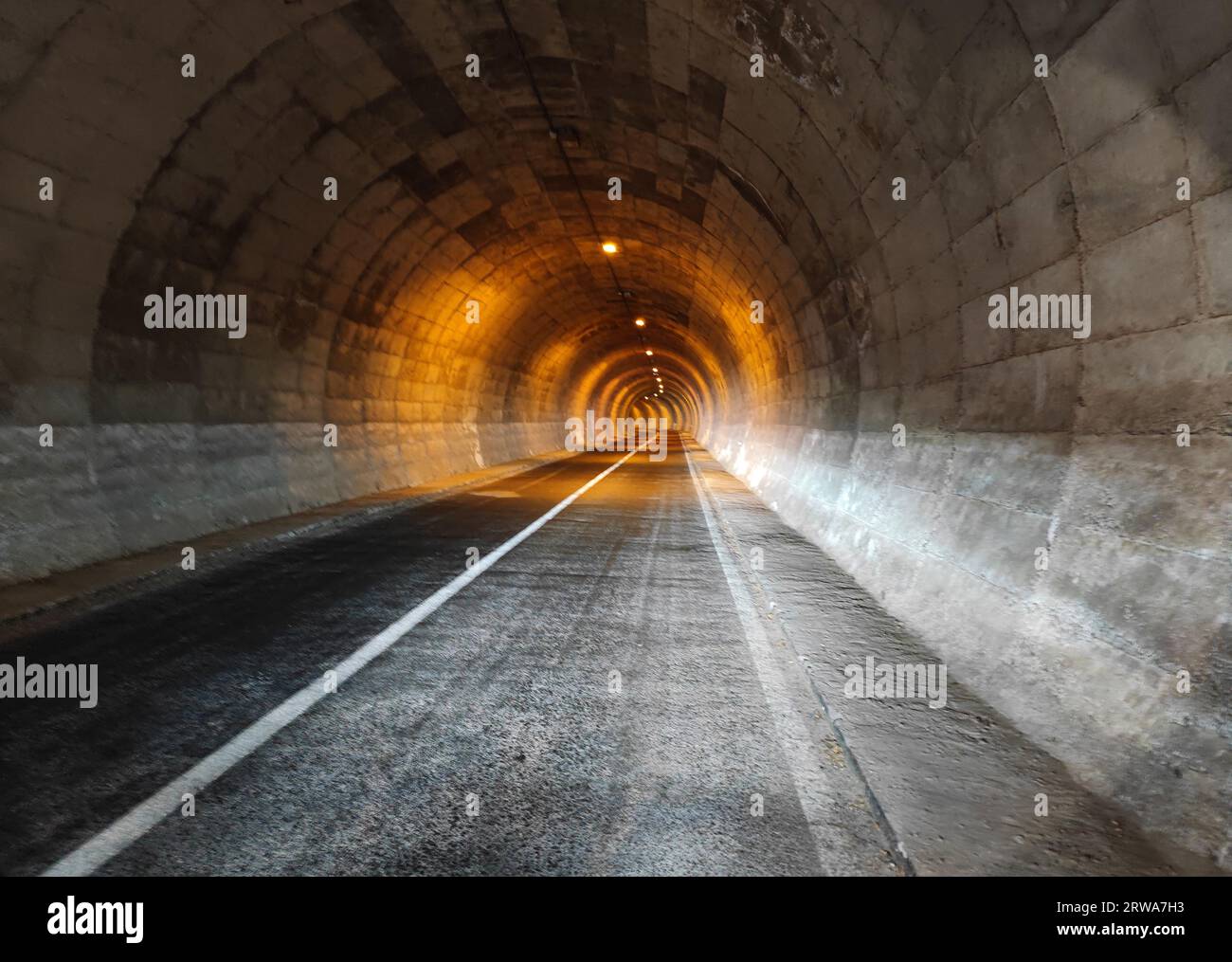 tunnel di cemento illuminato arancione che scompare dietro una curva, vicino a cuenca, spagna Foto Stock