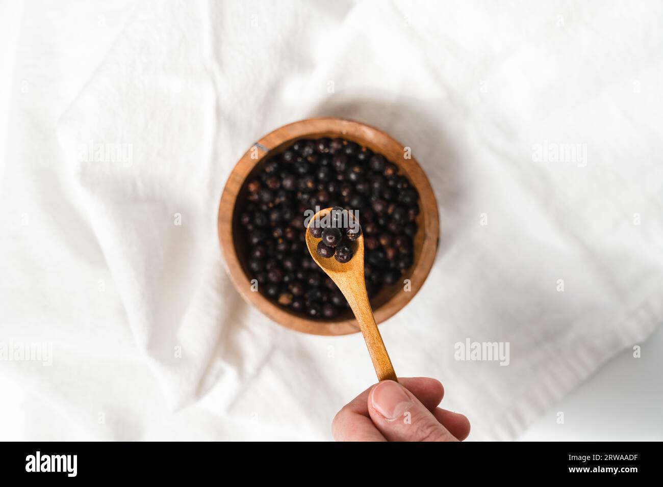 Un cucchiaio di bacche di ginepro per un ingrediente naturale per la cura della pelle Foto Stock