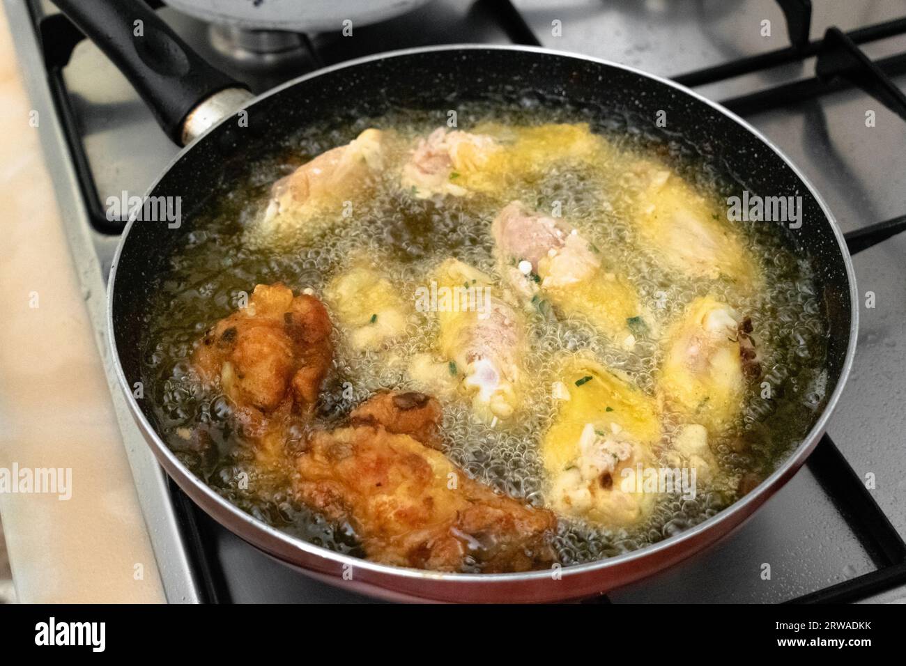 Friggere le ali di pollo in olio di palma vegetale caldo nella padella Foto Stock