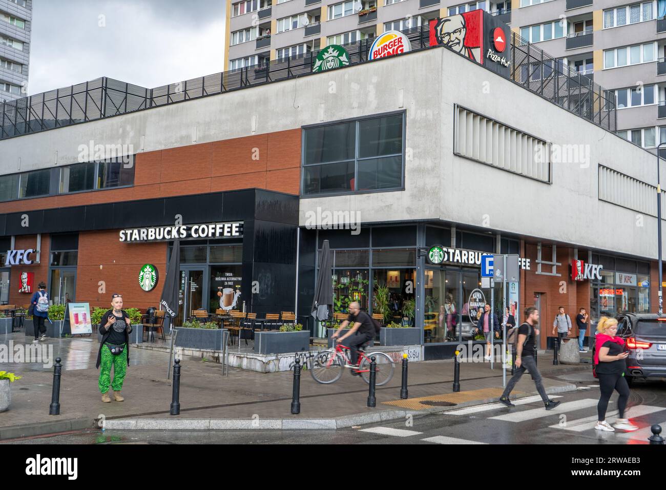 Caffetteria Starbucks, KFC e Burger King sotto un unico tetto. Logo di aziende concorrenti. Strada all'aperto. Cartello vetrina. Polonia, Varsavia - 28 luglio 2023 Foto Stock