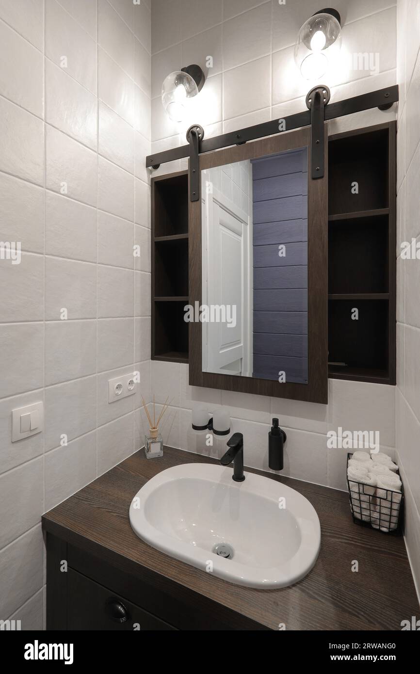 Rubinetto con lavabo in ceramica e specchio all'interno del bagno Foto Stock Rubinetto con lavabo in ceramica e specchio all'interno del bagno Foto Stock