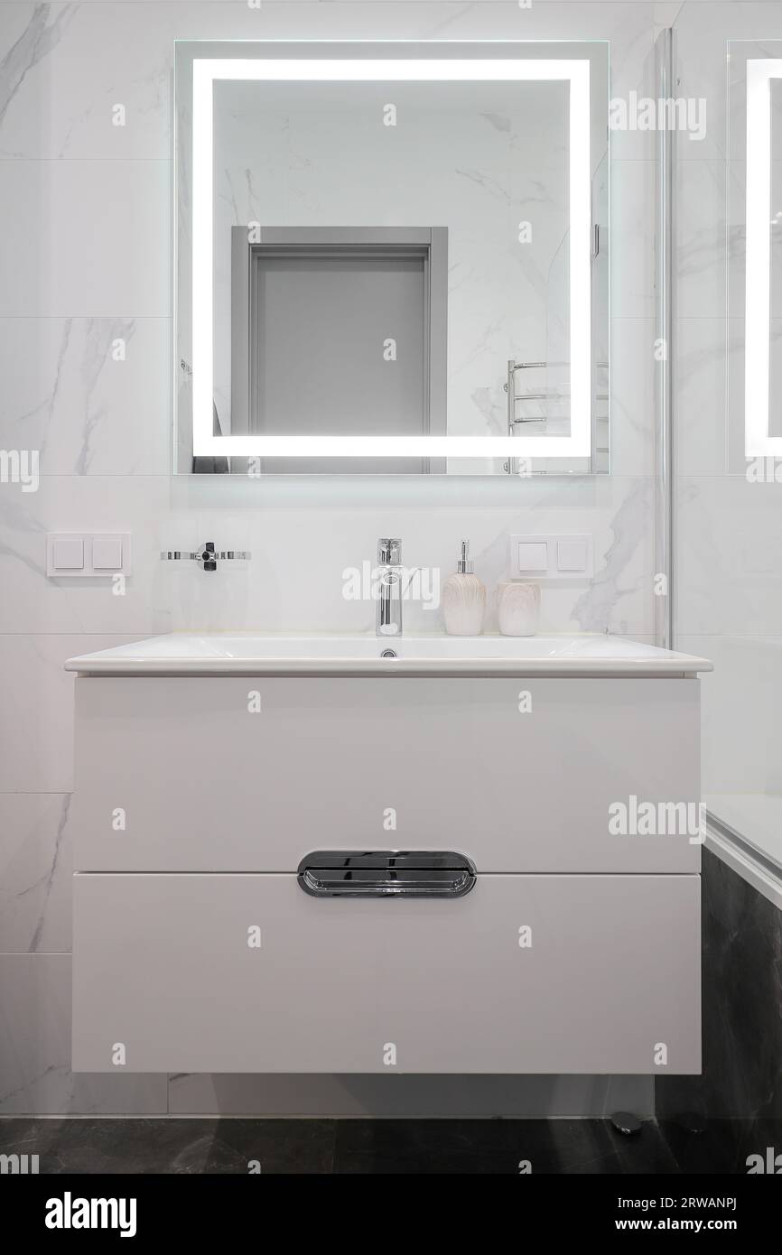 Rubinetto con lavabo in ceramica e specchio all'interno del bagno Foto Stock Rubinetto con lavabo in ceramica e specchio all'interno del bagno Foto Stock