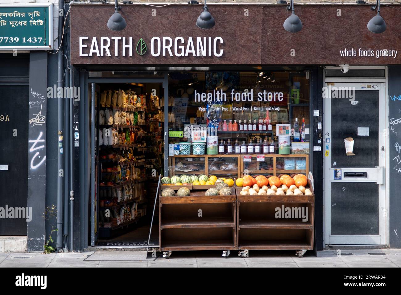 Scena di strada nell'East End, lungo Bethnal Green Road, dove molte piccole imprese e negozi indipendenti forniscono l'area, tra cui questo negozio di cibo biologico il 16 agosto 2023 a Londra, Regno Unito. Foto Stock