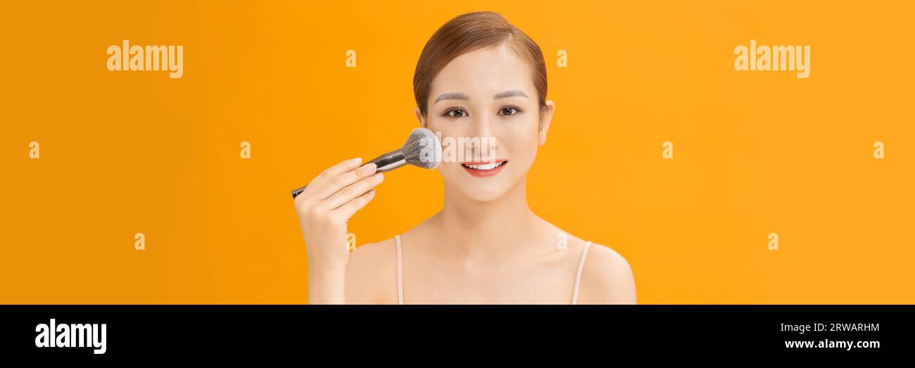 Giovane donna che usa il pennello, applica il trucco sullo sfondo dello striscione Foto Stock