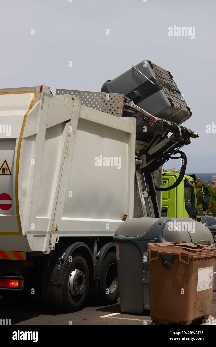 Un camion per la raccolta dei rifiuti che raccoglie i contenitori lateralmente e automaticamente sulla strada durante il giorno Foto Stock Un camion per la raccolta dei rifiuti che raccoglie i contenitori lateralmente e automaticamente sulla strada durante il giorno Foto Stock