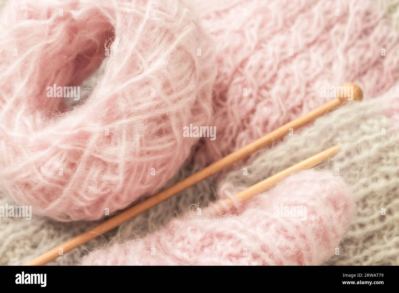 Aghi per filati e maglia, vista dall'alto. Filo di lana grigio e rosa con aghi. Uncinetto per maglieria. Modello a maglia. Concetto di ricettatura. Pullover fatto a mano. Foto Stock