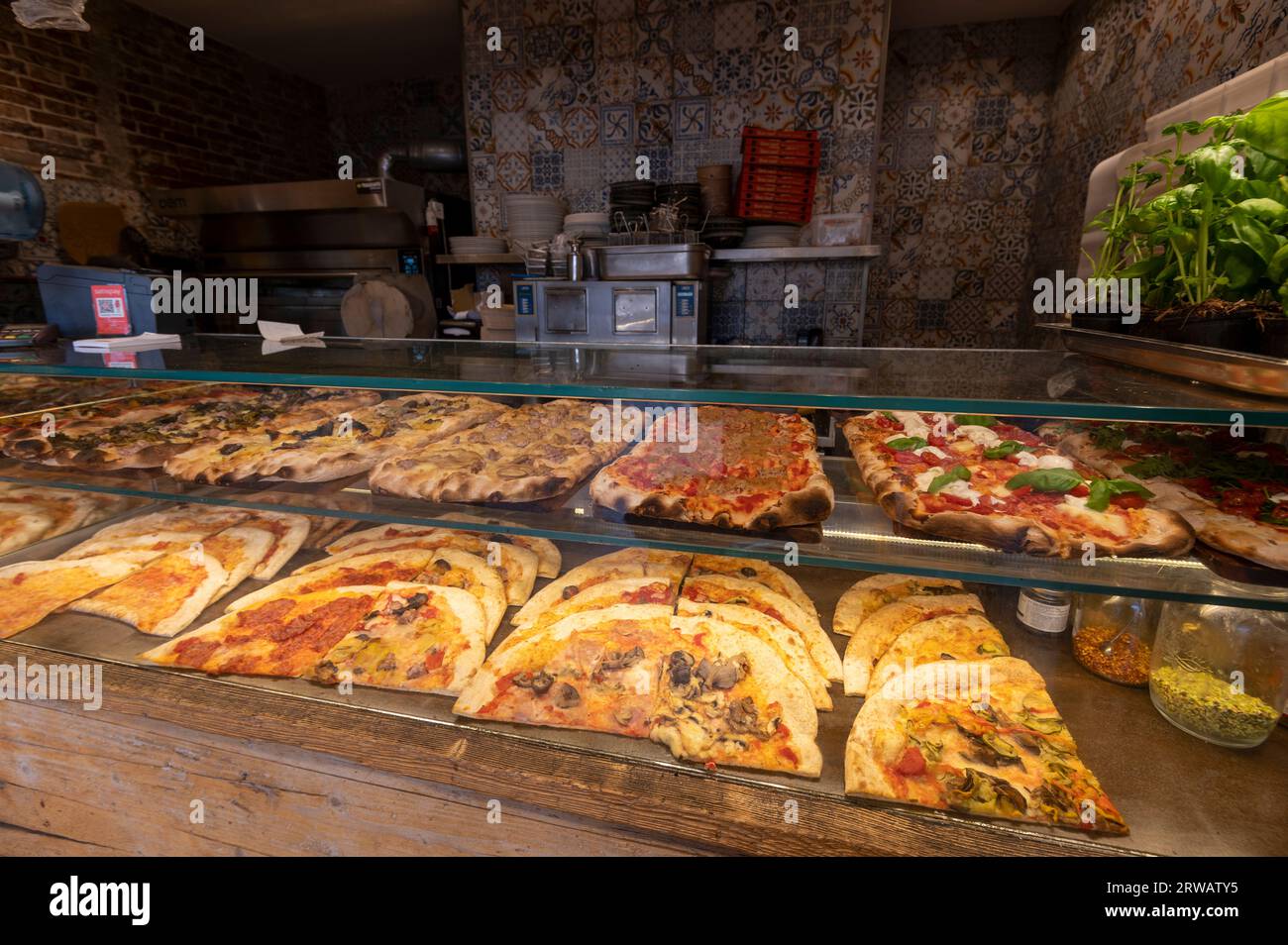 Una vetrina calda di una selezione di porzioni di pizza appena sfornate in vendita a Bologna, nella regione Emilia-Romagna del Nord Italia, Foto Stock