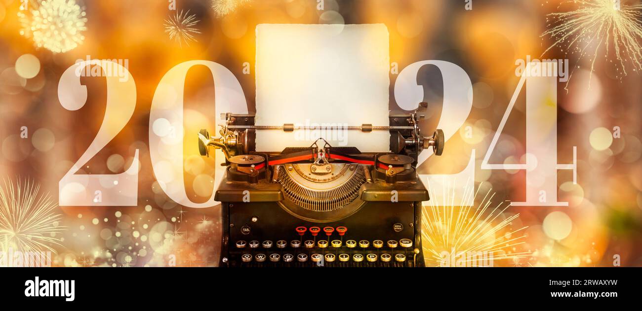 Annuncio del nuovo anno 2024 con macchina da scrivere, sfondo dorato sfocato e fuochi d'artificio Foto Stock