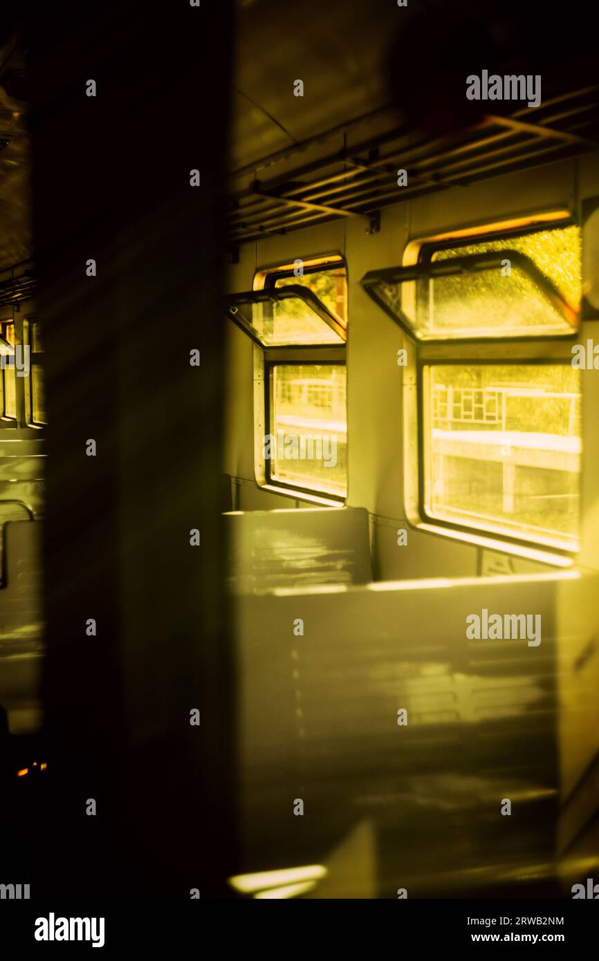 Una carrozza vuota di un vecchio treno, con raggi luminosi di luce solare calda che illuminano attraverso le sue finestre in un giorno d'estate. Il viaggio, la nostalgia e il Foto Stock