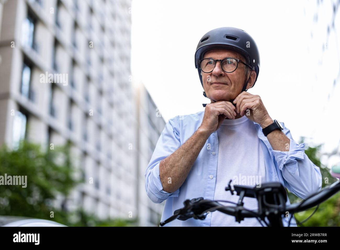 Uomo maturo che indossa il casco prima di andare in bicicletta in città Foto Stock