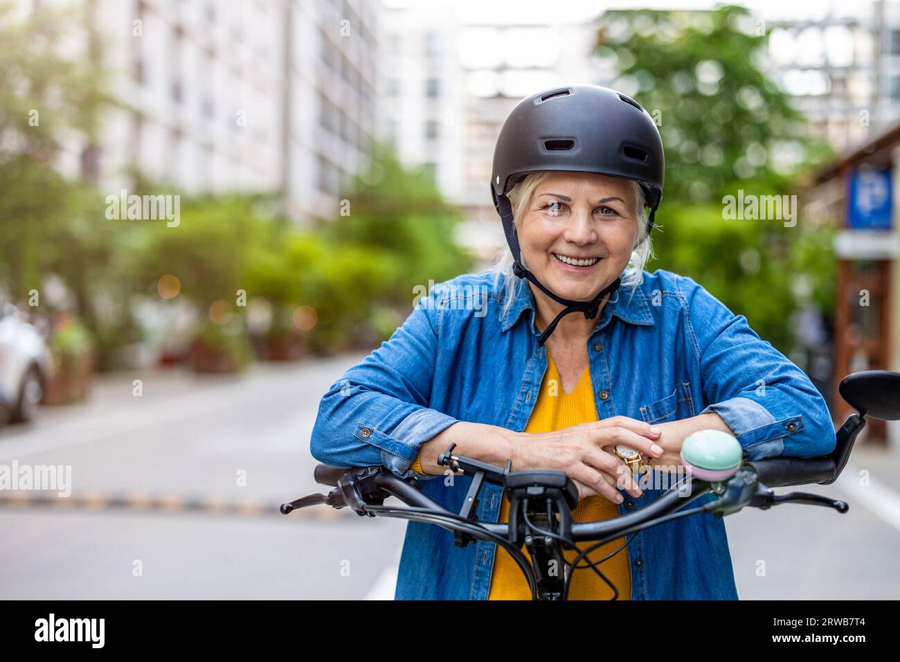 Ritratto di una donna anziana che indossa il casco mentre si va in bicicletta in città Foto Stock