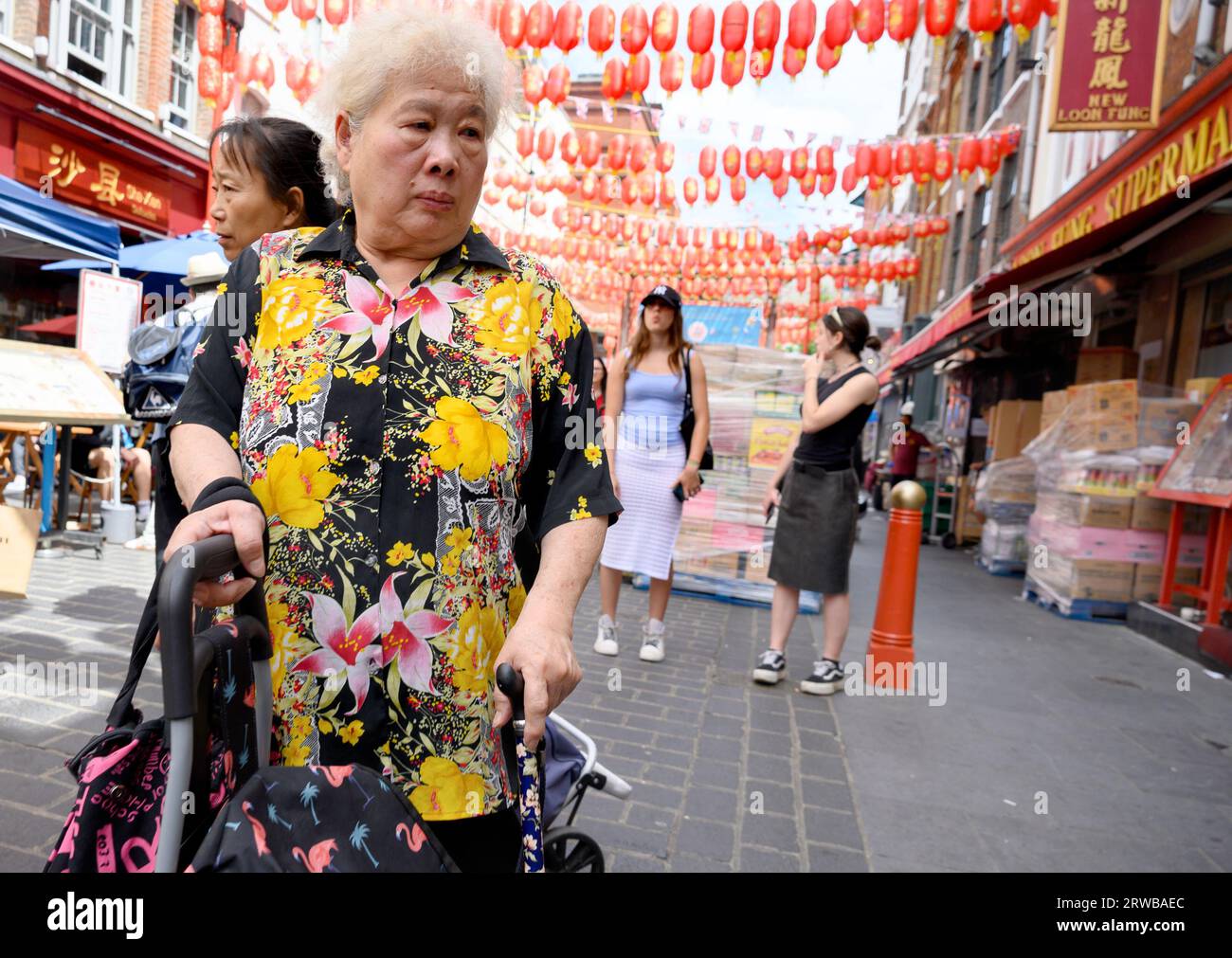 Londra, Regno Unito. Anziana donna cinese a Chinatown che indossa un luminoso top fiorito Foto Stock