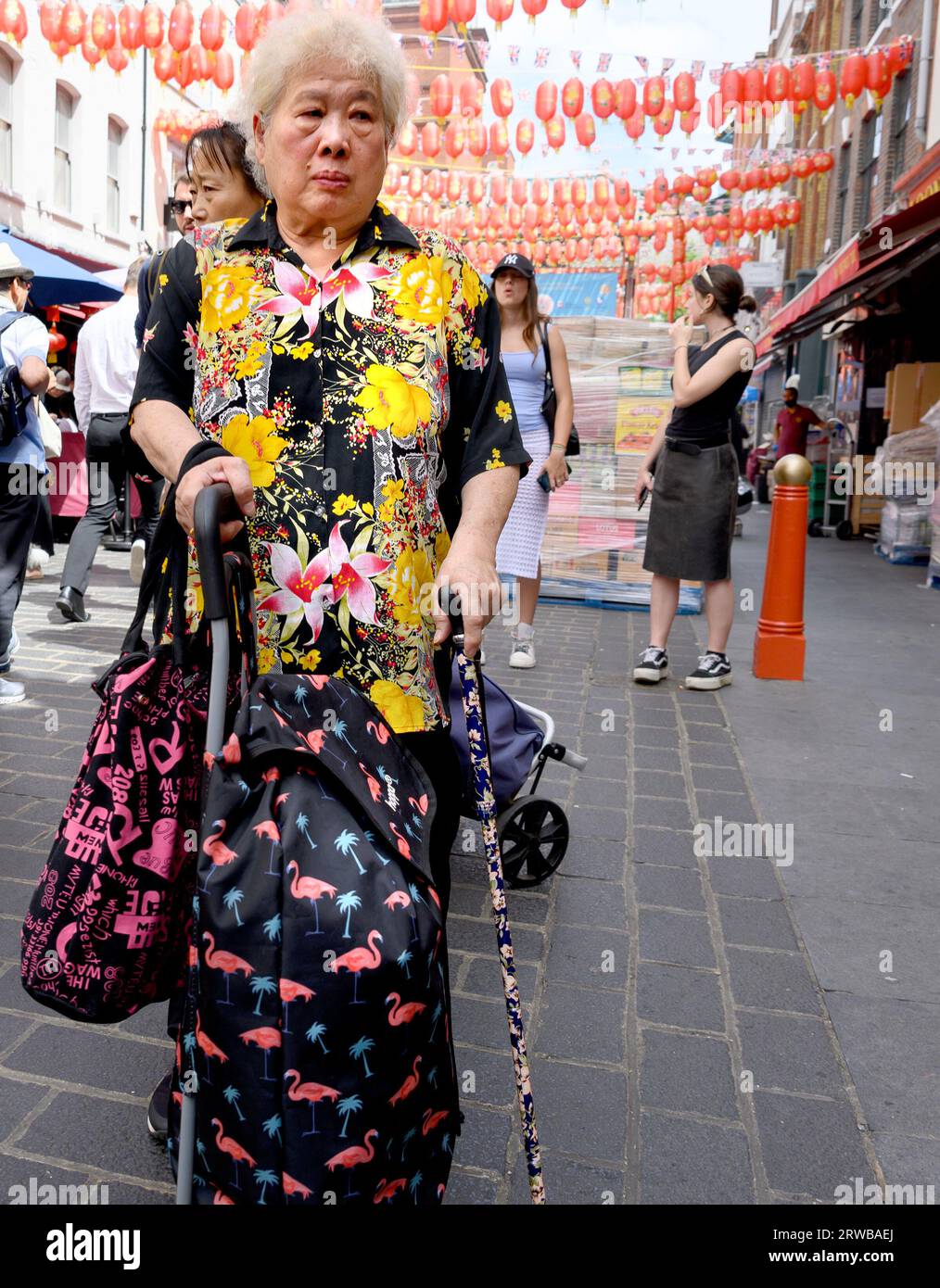 Londra, Regno Unito. Anziana donna cinese a Chinatown che indossa un luminoso top fiorito Foto Stock