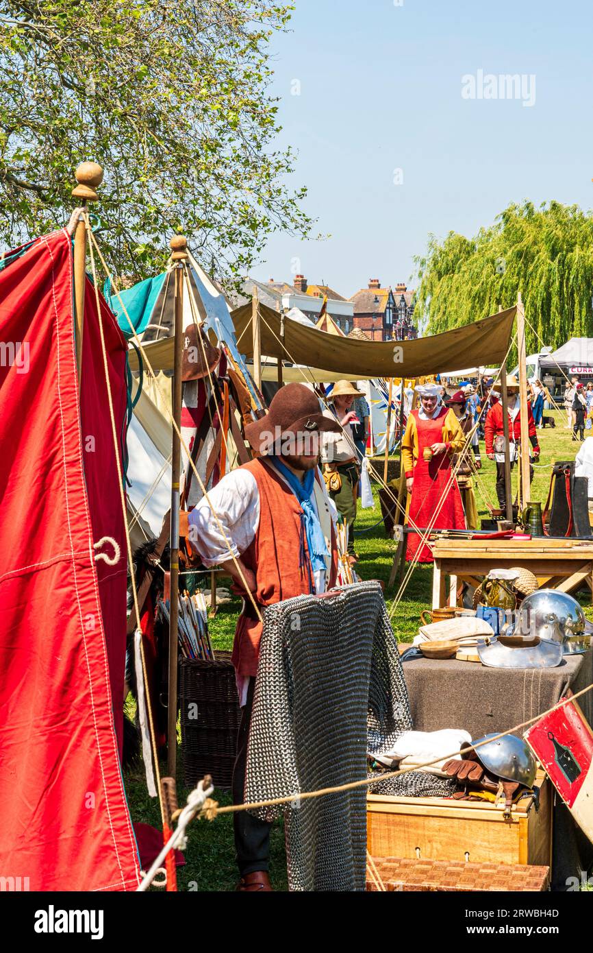 Ammira una fila di tende e tavoli allestiti per esporre vari oggetti e mestieri in un evento storico medievale vivente nella città di Sandwich nel kent. Soleggiato Foto Stock