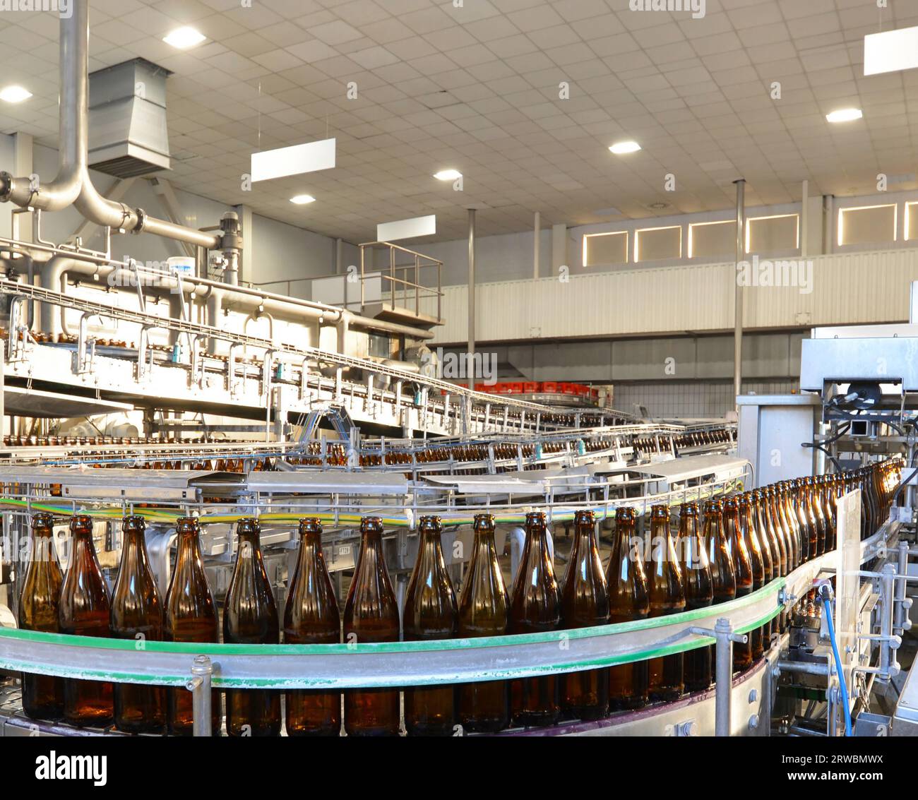 Bottiglie di birra sulla linea di montaggio in una birreria moderna - impianto industriale nell'industria alimentare Foto Stock