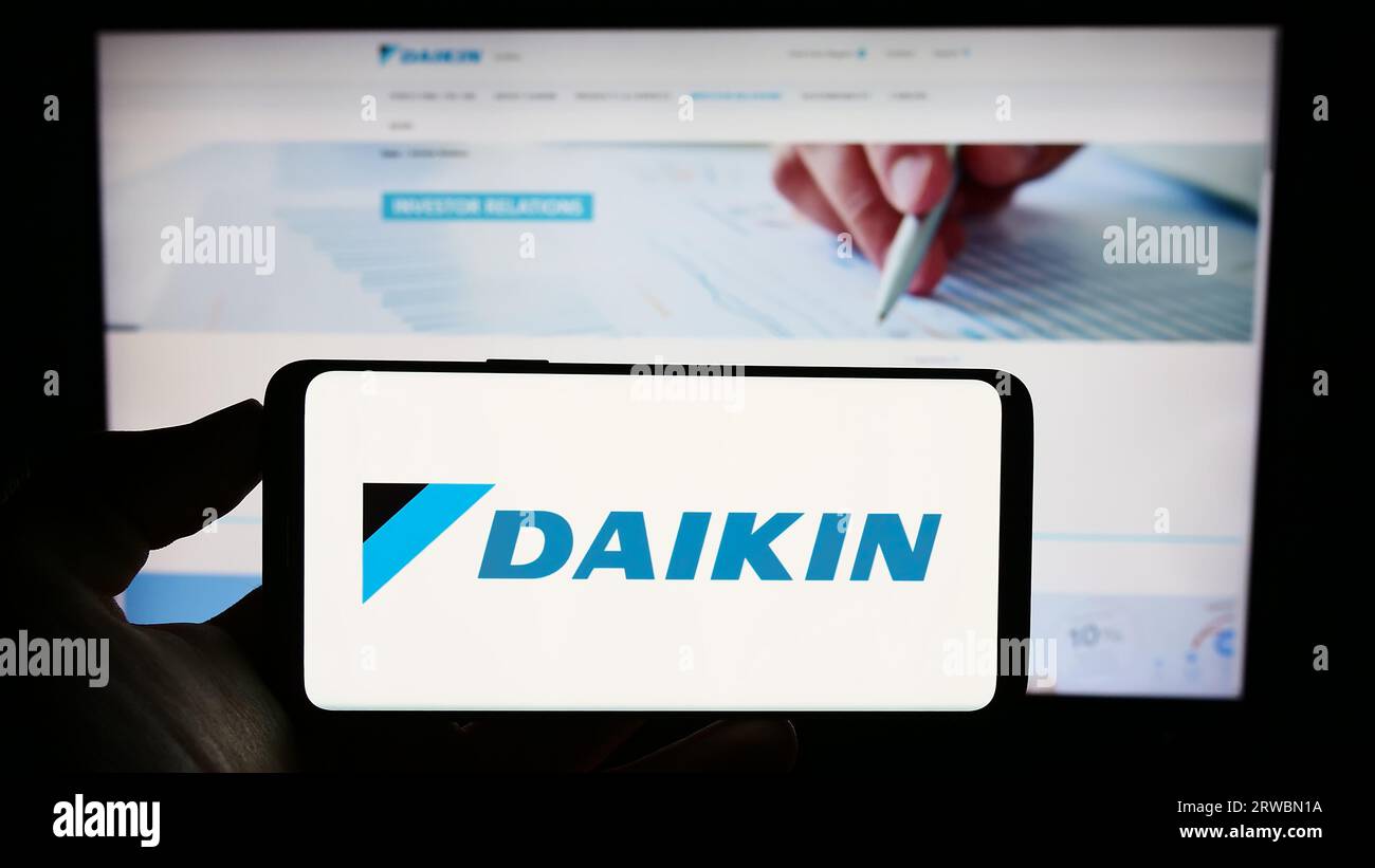 Persona che possiede un telefono cellulare con il logo dell'azienda giapponese Daikin Industries Ltd. Sullo schermo davanti alla pagina Web aziendale. Concentrarsi sul display del telefono. Foto Stock
