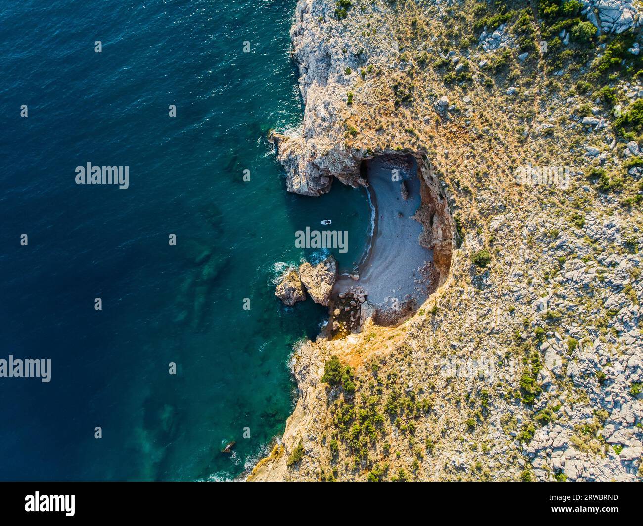 Vista dall'alto di uno splendido porto sul mare. Laguna con acqua blu scuro. Onde vicino alla costa rocciosa e alla barca Foto Stock