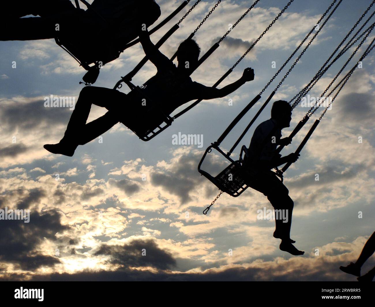 La gente cavalca su una giostra. Sagome di persone che cavalcano su una giostra al tramonto. Foto Stock