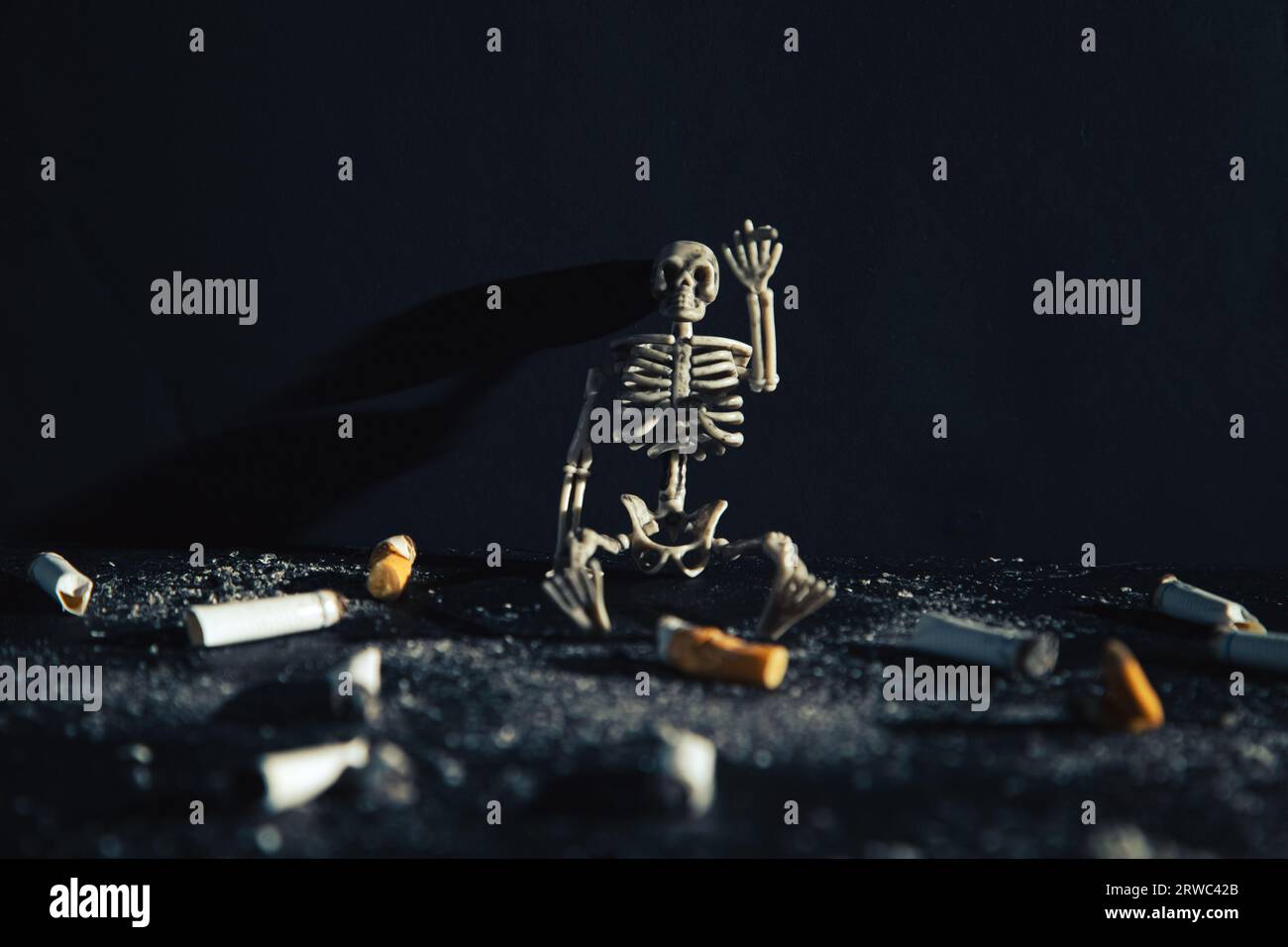 Lo scheletro umano siede con una sigaretta in una stanza buia. Concetto anti-tabacco. Fumare uccide. Foto Stock