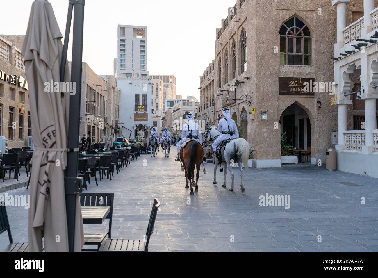 Doha, Qatar - 17 ottobre 2022: Polizia turistica in abiti tradizionali del Qatar pattuglia lungo la passerella nel Souq Wakif. Foto Stock