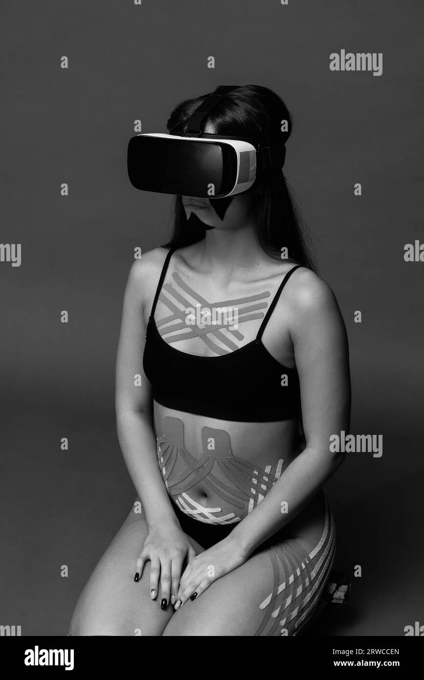Bella giovane donna che usa occhiali VR. Realtà virtuale. Nastri kinesio di cosmetologia. Benessere. Adatta. Foto di alta qualità Foto Stock