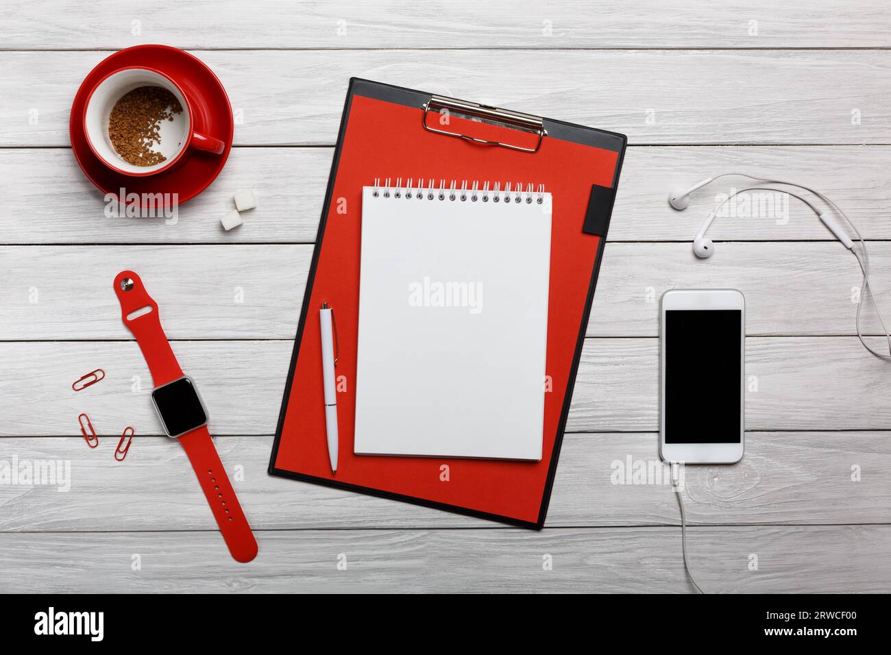 tazza bianca di caffè rossa con orologio da tavolo per notebook processo di funzionamento delle cuffie all'inizio della giornata lavorativa Foto Stock