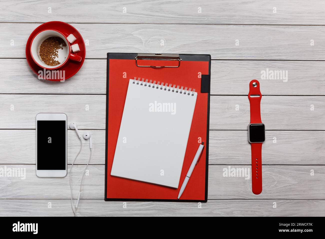 tazza bianca di caffè rossa con orologio da tavolo per notebook processo di funzionamento delle cuffie all'inizio della giornata lavorativa Foto Stock