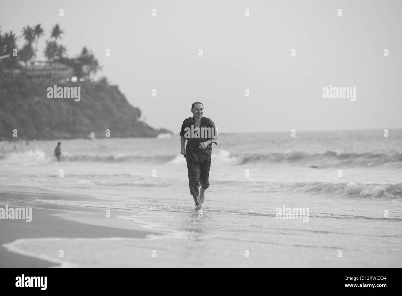 Giovane uomo formazione sulla spiaggia di mattina. Giovane uomo su run mattutino all'esterno. Foto Stock