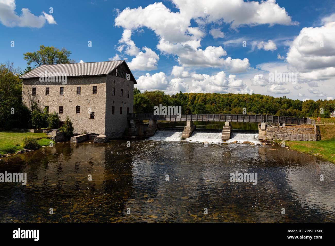 Lang Grist Mill e ponte sulla diga della cascata al Pioneer Village sul fiume Indian Keene, Ontario, Canada. Foto Stock