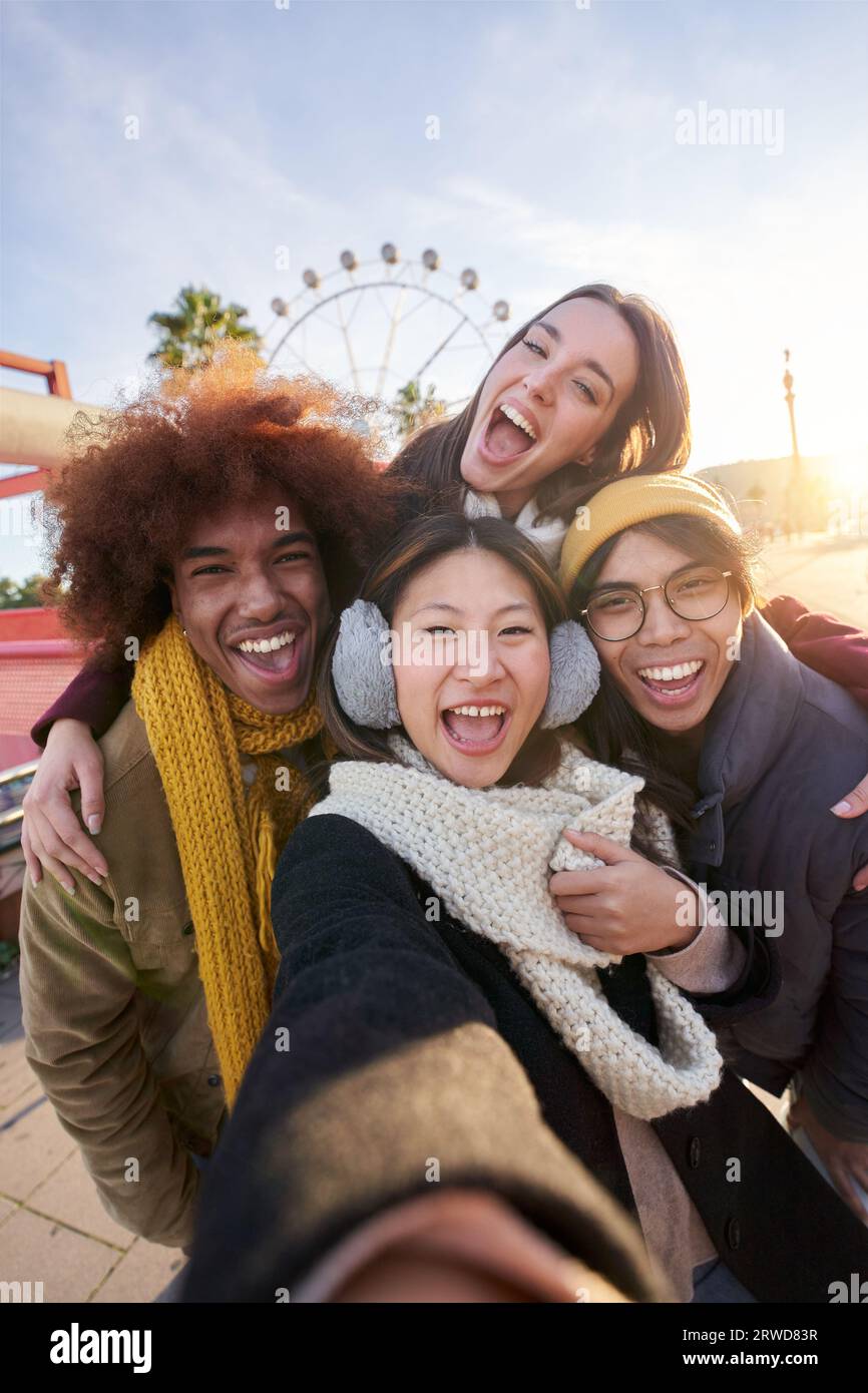 Gruppo di amici multirazziali eccitati in verticale che scattano selfie divertenti che sembrano sorridere alla fotocamera. Foto Stock