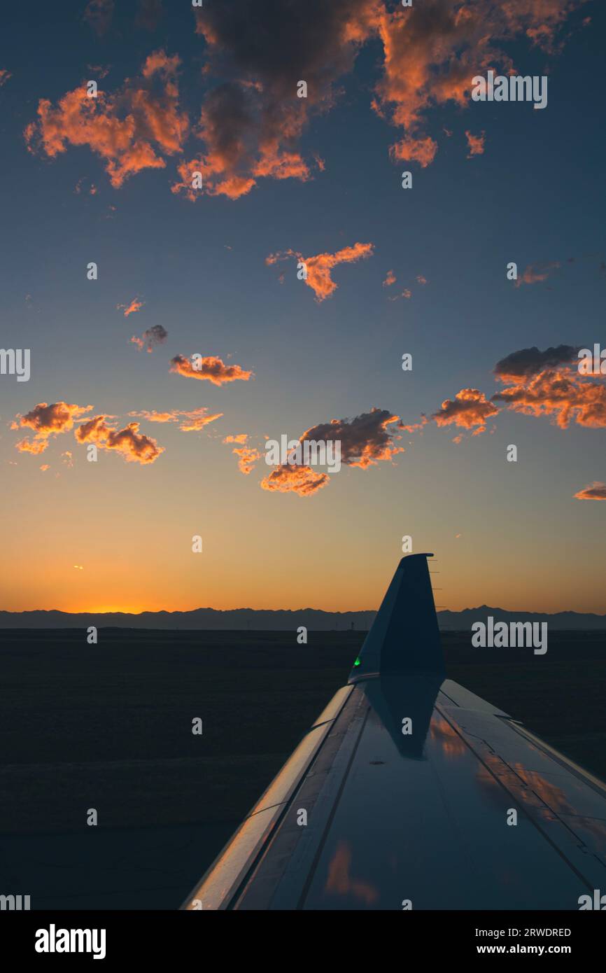 Il tramonto sull'aeroporto di Denver, che si riflette nell'ala metallica dell'aeroplano. Foto Stock