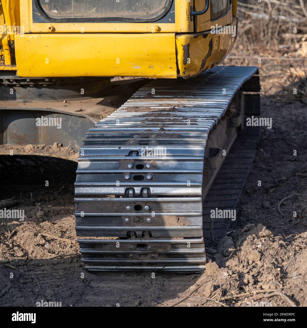 Primo piano di un cingolo in acciaio vecchio e usurato su un escavatore usato ma funzionante. Foto Stock