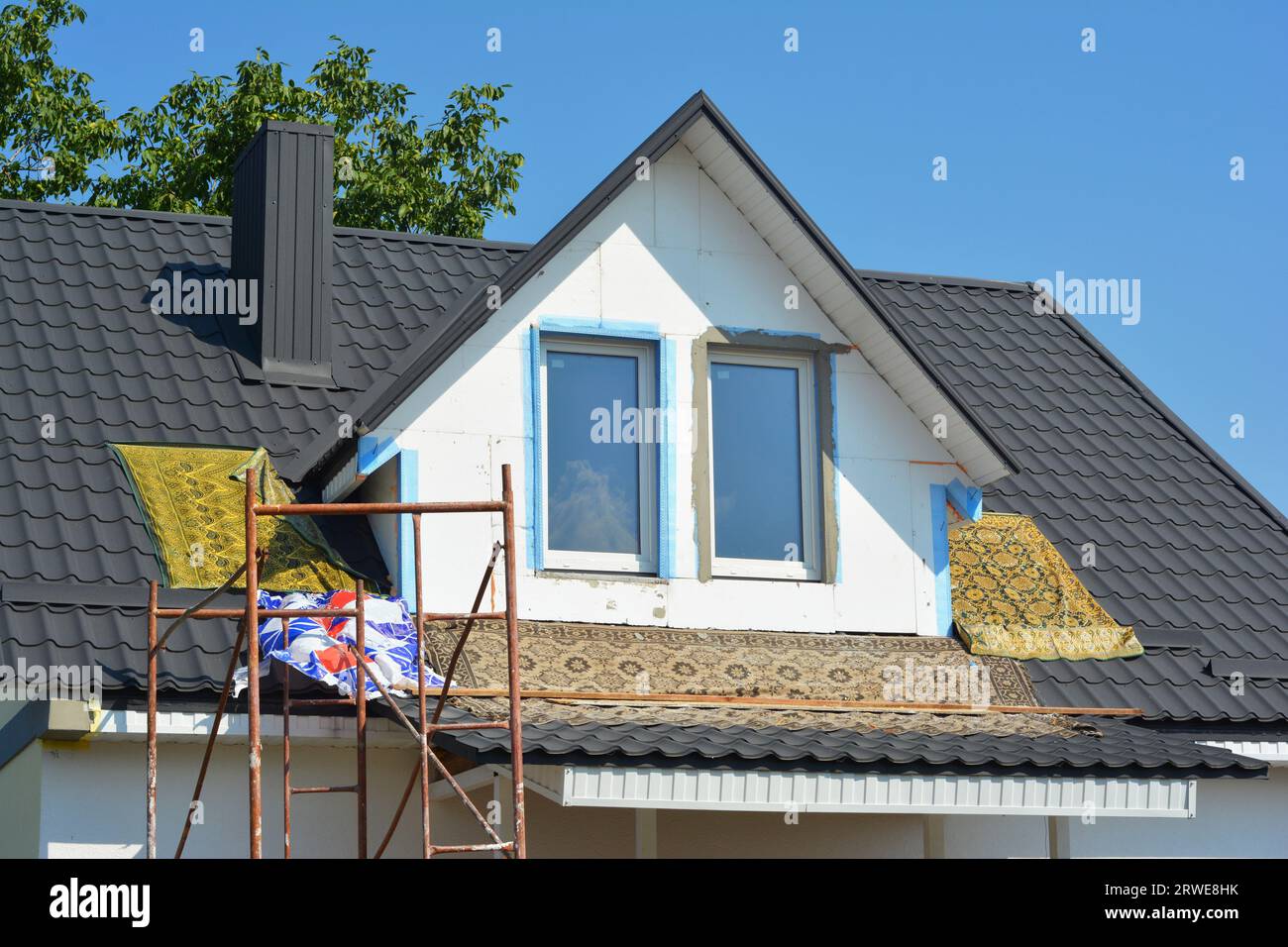 Isolamento della finestra dormitorio della casa con pannelli in schiuma rigida bianca durante la ristrutturazione della casa. Casa con nuovo tetto in metallo. Foto Stock