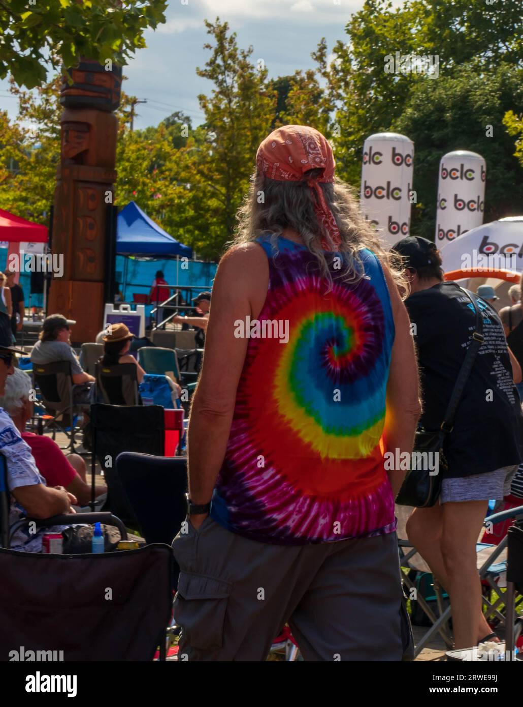 Uomo a un festival musicale con camicia tinto con cravatta, fazzoletto e capelli lunghi. Foto Stock
