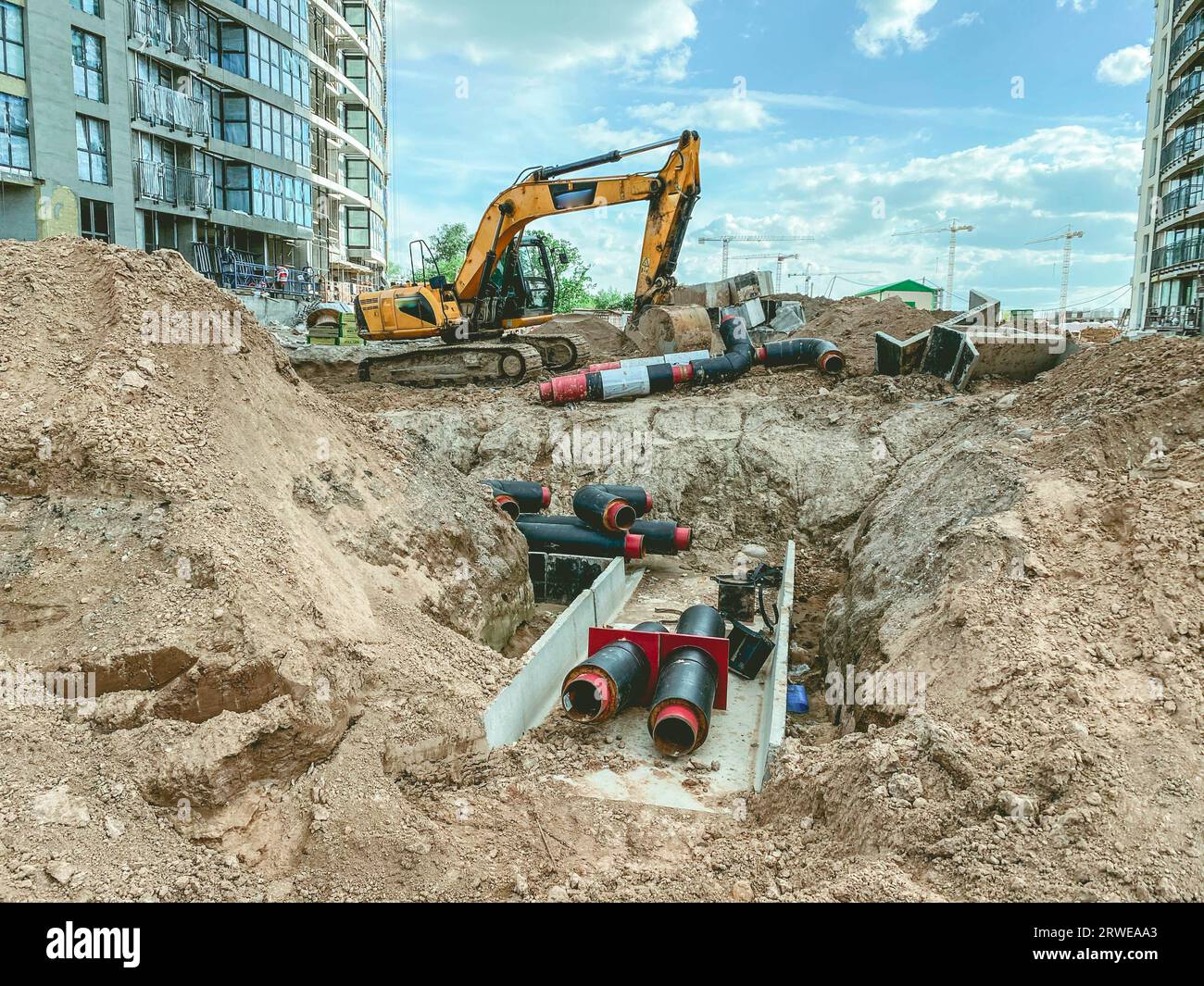 costruzione di una nuova zona della città. fossato di costruzione, posa di cavi e comunicazioni sotterranee. seppellire grandi tubi rotondi nella sabbia. Foto Stock