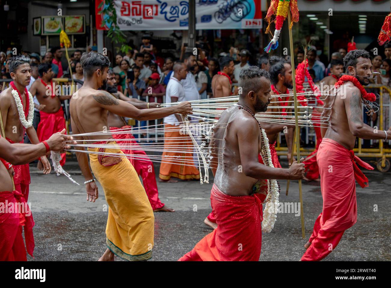 I ballerini Kavadi (indù) con numerosi piercing del corpo a gancio si esibiscono lungo una strada di Kandy in Sri Lanka durante il giorno Perahera. Foto Stock