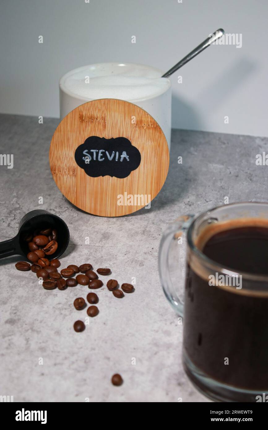 Una ciotola con dolcificante per la stevia e un bicchiere di caffè nero, sfondo grigio Foto Stock